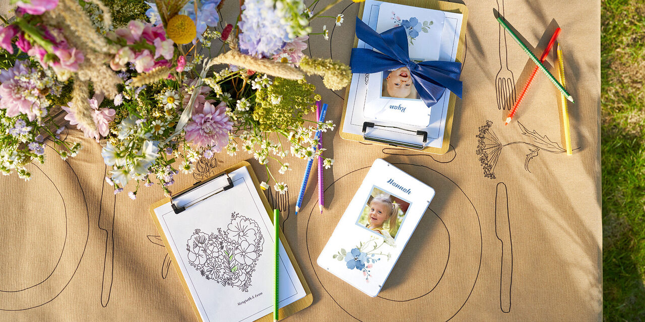 Auf einem Tisch liegen Farbstifte in einer Metallbox im floralen Design mit Kinderfoto und ein Bild zum Ausmalen.