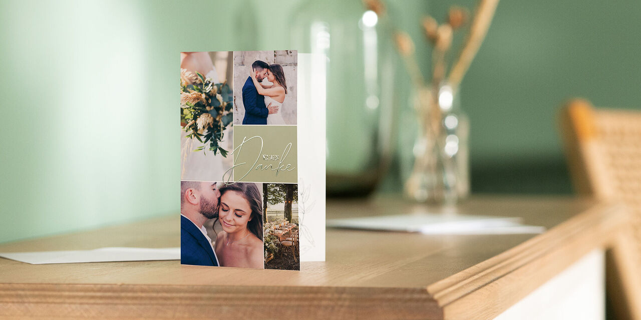 Eine Dankeskarte im Hochformat steht aufgeklappt auf einer Kommode. Auf dem Cover befinden sich vier Fotos des Brautpaares in einem collageartigen Layout. Ausserdem ist der Spruch «Wir sagen Danke» auf grünem Grund zu sehen.